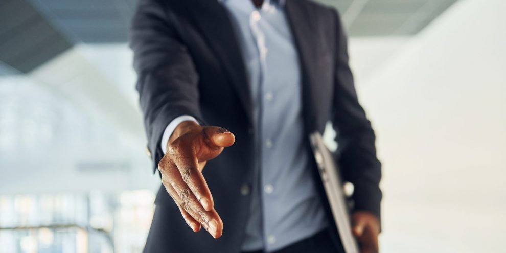 Successfull agreement. Young african american businessman in black suit is indoors